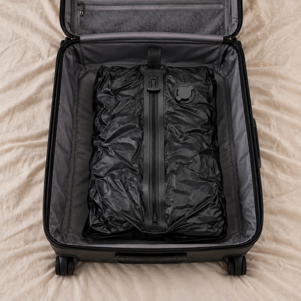The same clothes vacuum-packed in one flat black bag inside the suitcase