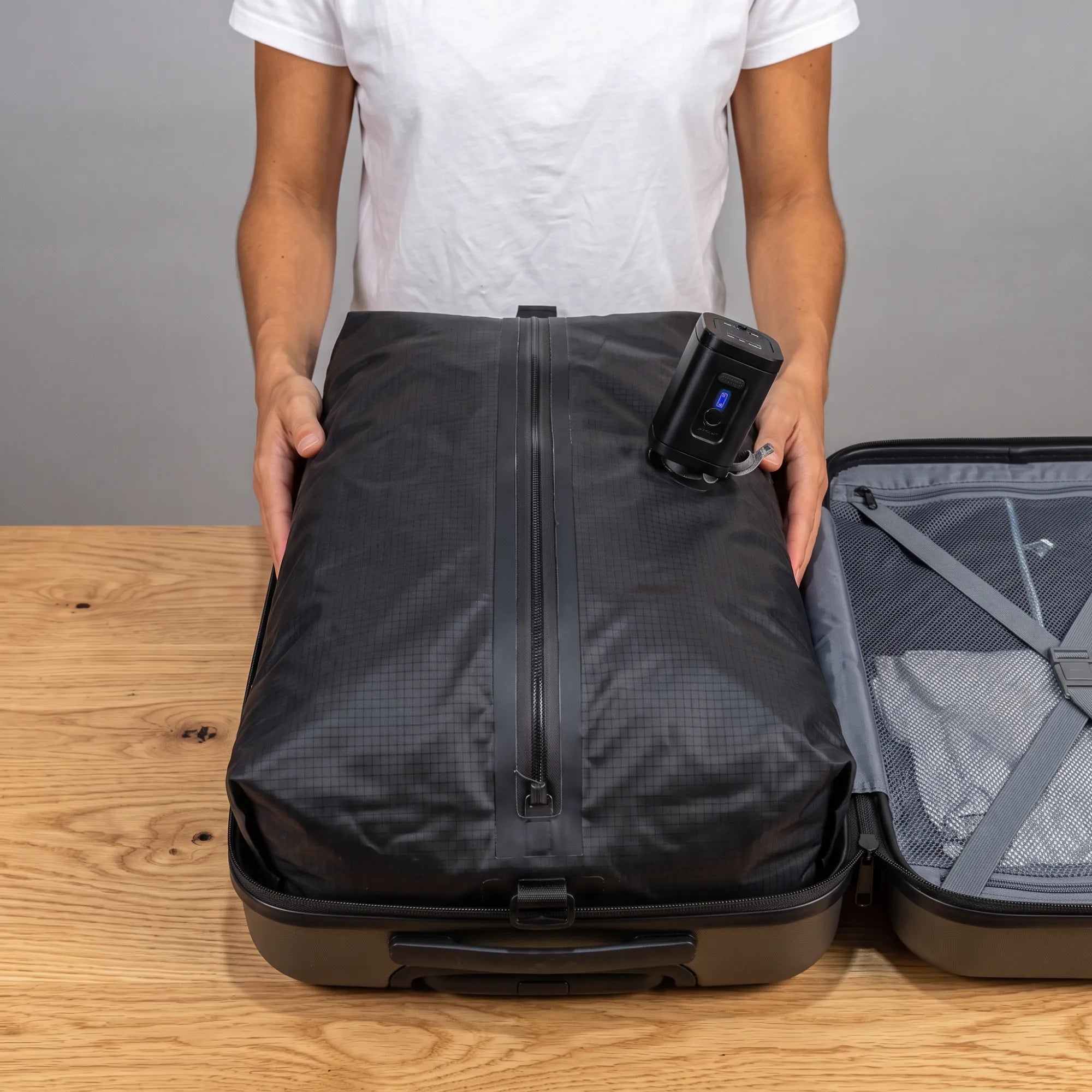The full black bag, zipped shut, in an open suitcase with the pump on its valve